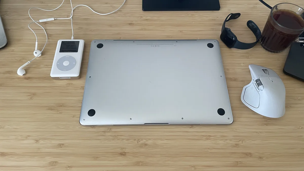 Underside of a closed M1 MacBook Air on a desk with its four rubber feet visible