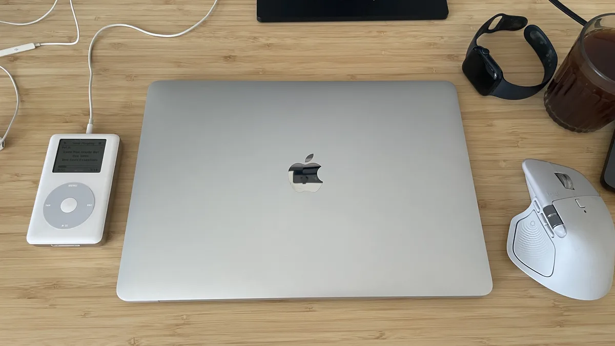 Closed M1 MacBook Air on a desk next to an iPod, Apple Watch, coffee, and mouse