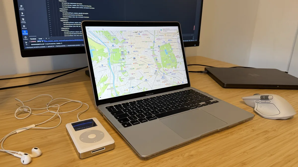 Five-year-old M1 MacBook Air on a desk with an iPod, external display, headphones, and peripherals.