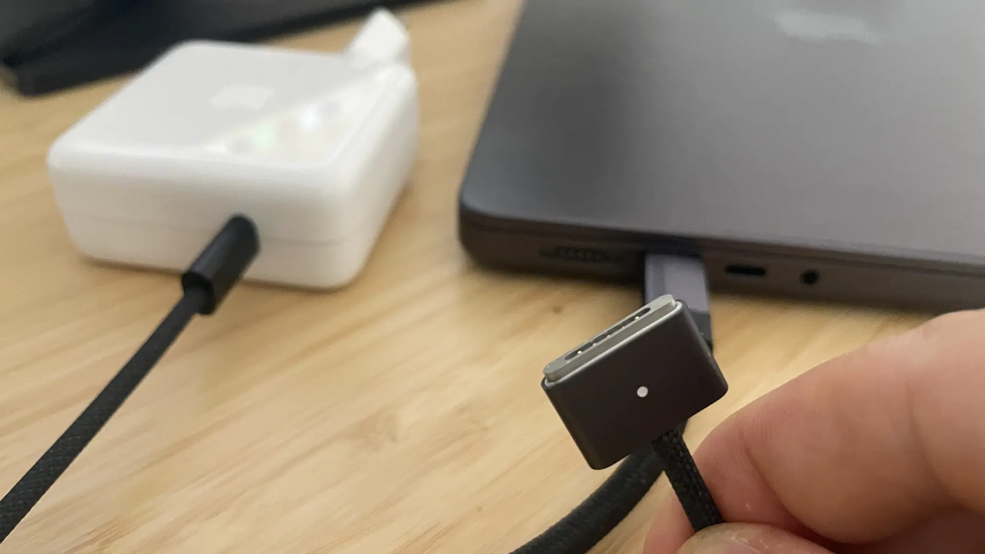 Close-up of braided MagSafe cable and USB-C cable beside a MacBook Pro M4 Pro